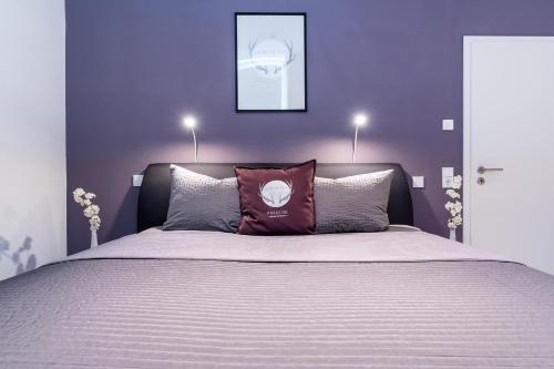 - une chambre avec un grand lit aux murs violets dans l'établissement Parkside Boutique Appartements, à Herbolzheim