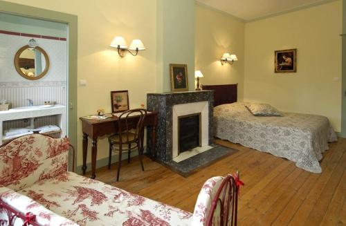 a bedroom with a fireplace and a bed and a desk at Le Domaine De Pomone in Woinville