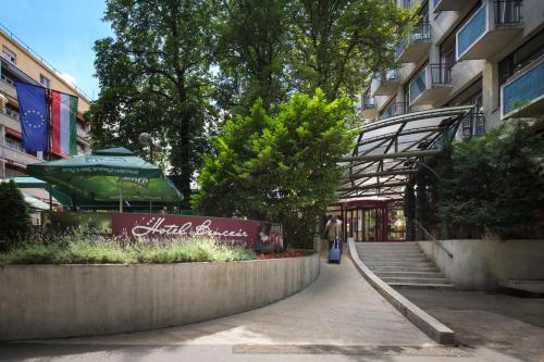 a walkway leading to a building with a green umbrella at Benczur Hotel in Budapest