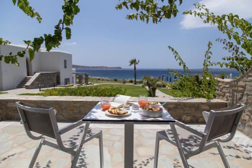 una mesa con comida y bebida en un patio con vistas al océano en Poseidon of Paros Hotel & Spa, en Chrissi Akti