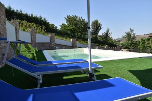 a swimming pool in a yard with blue chairs at B&B La Dolce Vita in Priocca