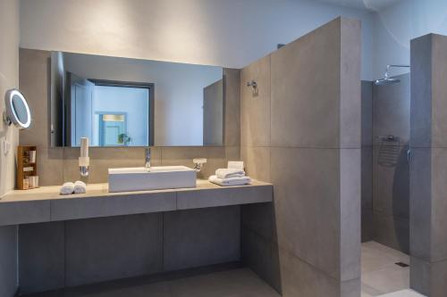 a bathroom with a sink and a mirror at Poseidon of Paros Hotel & Spa in Chrissi Akti