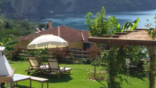 a group of chairs and an umbrella in a yard at Elina Apartments in Parga