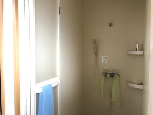 a bathroom with a shower with a towel hanging on the wall at Guest House Hennka Kyoto in Kyoto