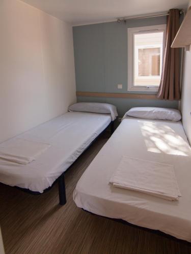 two beds in a small room with a window at Complejo Turístico & Camping Cabopino in Marbella