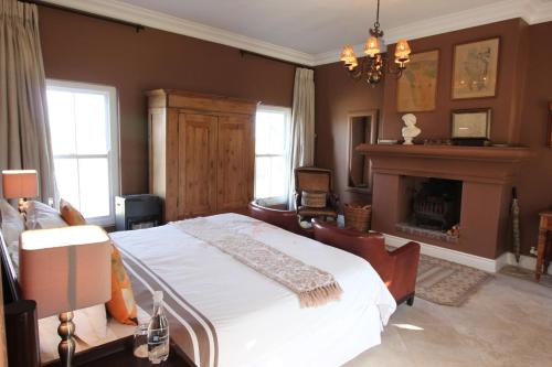 a bedroom with a large bed and a fireplace at Hawksmoor House in Stellenbosch