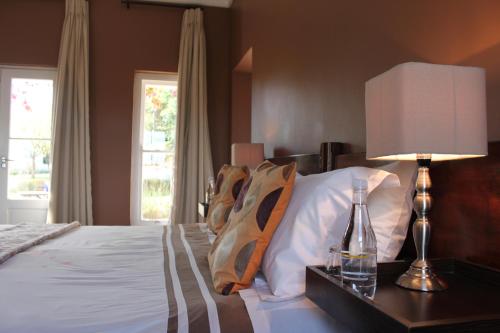 a bedroom with a bed with a lamp and pillows at Hawksmoor House in Stellenbosch