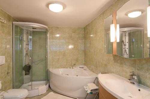 a bathroom with a tub and a sink and a shower at Apartments and Rooms Banić in Kranjska Gora