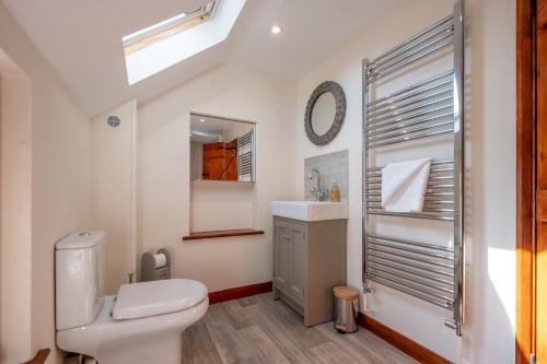 y baño con aseo, lavabo y espejo. en 3 Beach Cottages - Aldeburgh Coastal Cottages, en Thorpeness