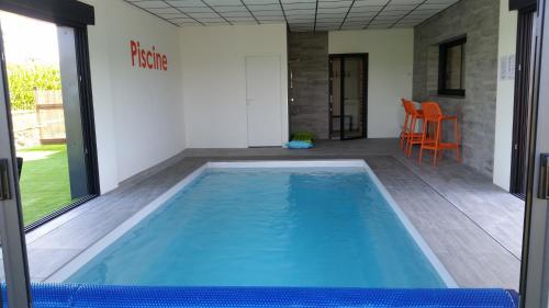 a swimming pool in a room with a table and chairs at La Ry'Bambelle in Les Herbiers