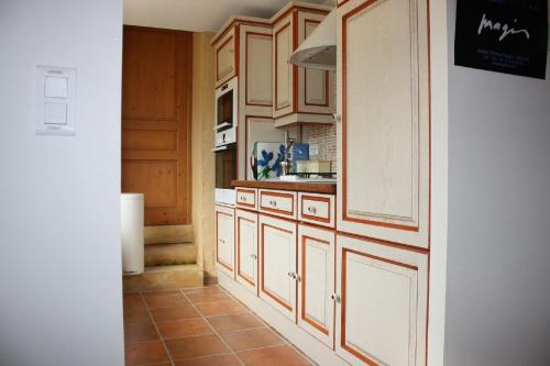 a kitchen with wooden cabinets and a tile floor at Cottage de La Mothe in Marnac