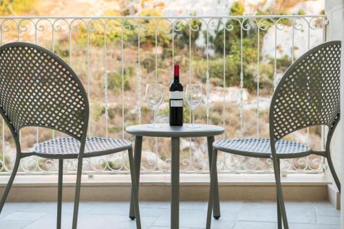 a bottle of wine sitting on a table with two chairs at Cesca's Boutique Hotel in Xlendi