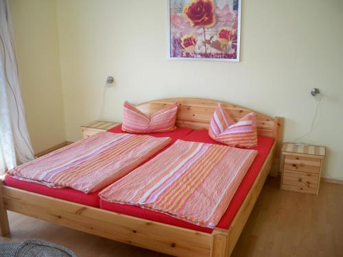 バンシンにあるMeereswogeのベッドルーム1室(ピンクとオレンジの枕が備わる木製ベッド1台付)