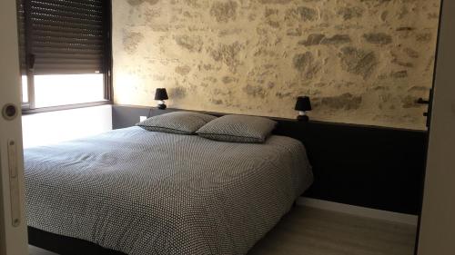 a bedroom with a bed with two pillows and a window at La Ry'Bambelle in Les Herbiers