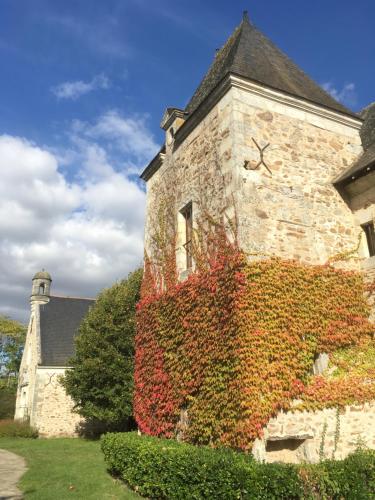 an ivy covered building with a clock on it at Manoir de Jouralem in Blaison