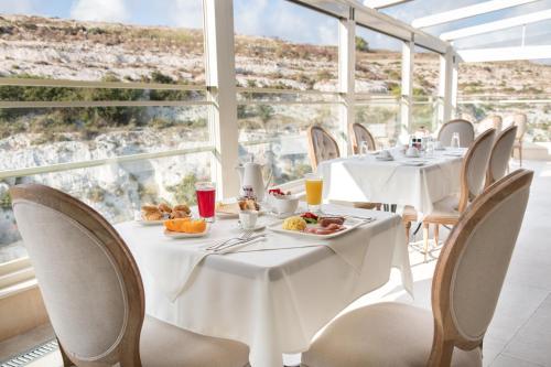 a restaurant with tables and chairs with food on them at Cesca's Boutique Hotel in Xlendi