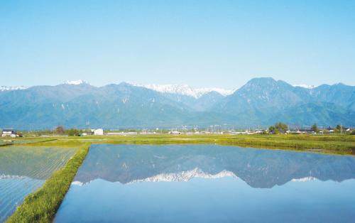 een waterlichaam met bergen op de achtergrond bij Azumino Ikeda Guesthouse in Azumino