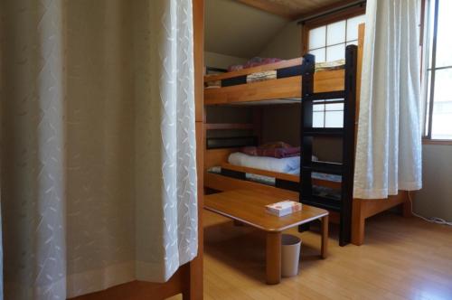 安曇野市にあるあづみの池田ゲストハウスの二段ベッド2台とテーブルが備わる客室です。