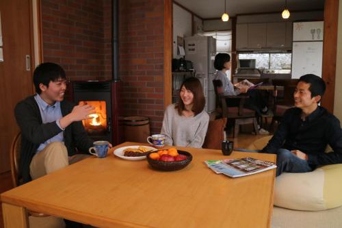 Un groupe de personnes assises autour d'une table dans l'établissement Azumino Ikeda Guesthouse, à Azumino