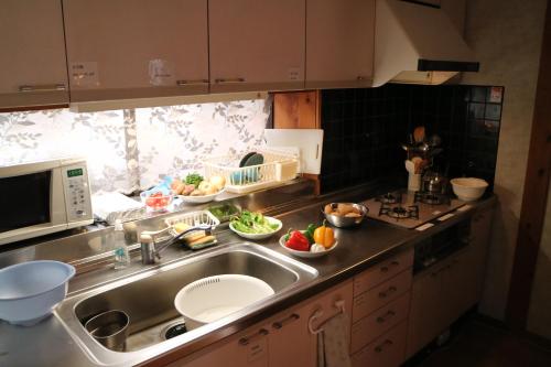 a kitchen with a sink and some bowls of fruit at Azumino Ikeda Guesthouse in Azumino
