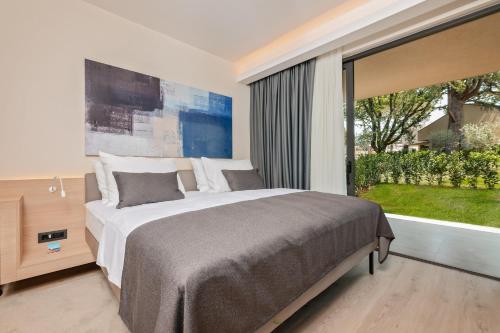 a bedroom with a large bed and a large window at Garden Suites Park Plava Laguna in Poreč