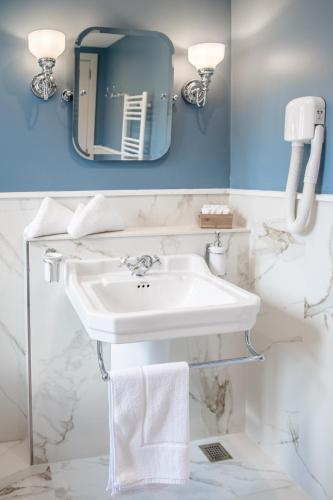 a white bathroom with a sink and a mirror at Cesca's Boutique Hotel in Xlendi