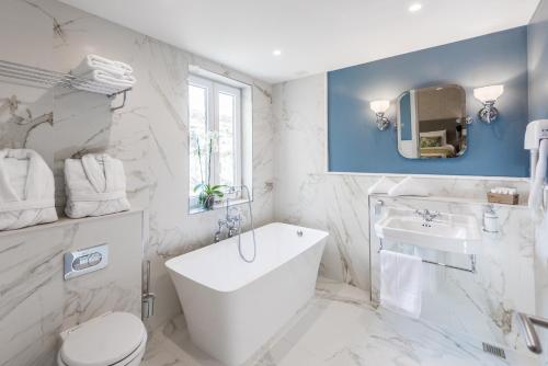 a white bathroom with a tub and a sink at Cesca's Boutique Hotel in Xlendi