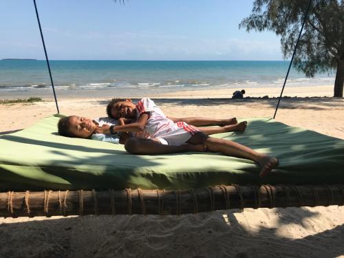 two people laying on a blanket on the beach at Mangrove Lodge in Zanzibar City