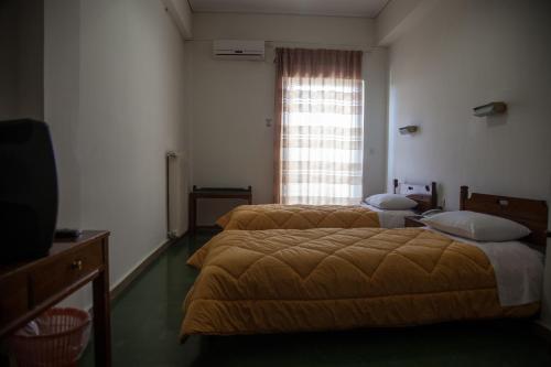 two beds in a room with a window at Hotel Liberty in Mesolongion