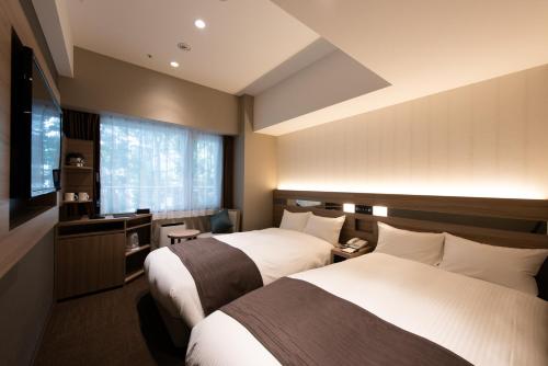 una camera d'albergo con due letti e una finestra di Hotel Hewitt Koshien a Nishinomiya