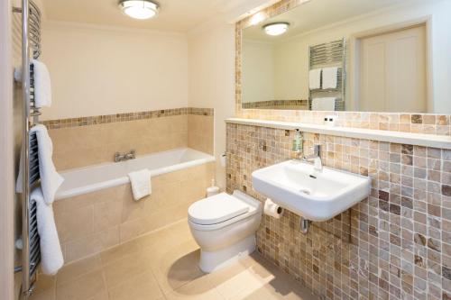 a bathroom with a toilet and a sink and a tub at Park Farm Hotel in Norwich