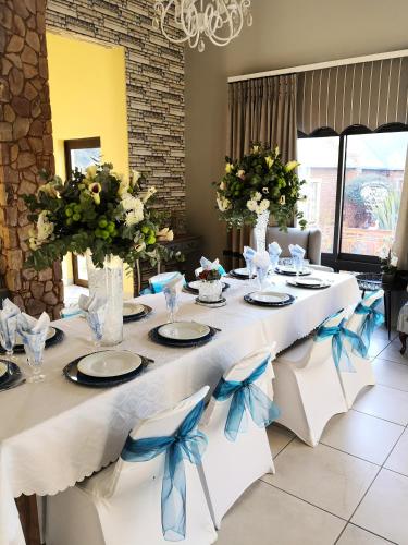 a long table with white chairs and blue bows at Van Dykshuis Guest House in Heidelberg