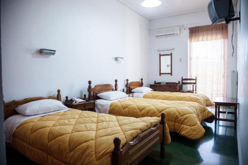 a room with three beds with yellow blankets at Hotel Liberty in Mesolongion