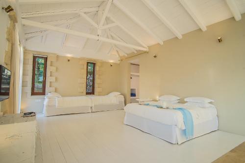 two beds in a large room with white walls at Icons Sea of Crete in Malia