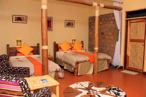a bedroom with two beds and a chair and a table at Lake Mulehe Gorilla Lodge in Kisoro