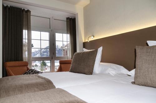 a bedroom with two beds and a large window at Hotel Presa in Riaño