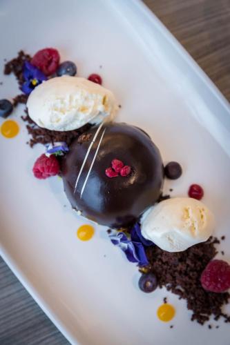 a dessert on a white plate with ice cream and berries at Maldron Hotel Dublin Airport in Cloghran