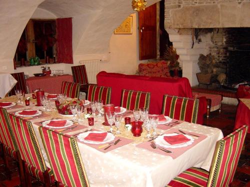 une table avec un tissu de table blanc et des chaises rouges dans l'établissement MANOIR de la RIVIERE, à Géfosse-Fontenay