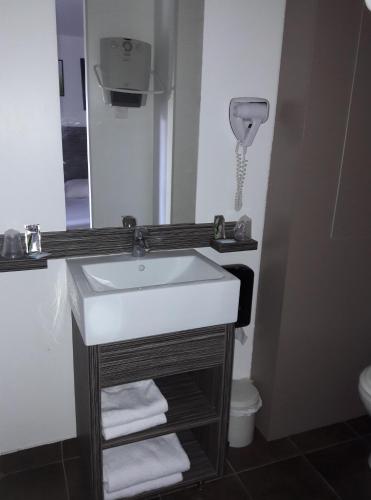 une salle de bain avec un lavabo et un miroir et des toilettes dans l'établissement Hôtel Le Cosy Blois Villebarou, à Blois