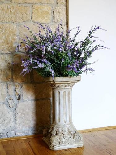 a vase filled with purple flowers sitting on a wooden floor at Apartment Naita in Sinj