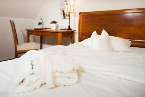 a bedroom with white towels on a bed with a desk at Landhaus Eggert in Münster