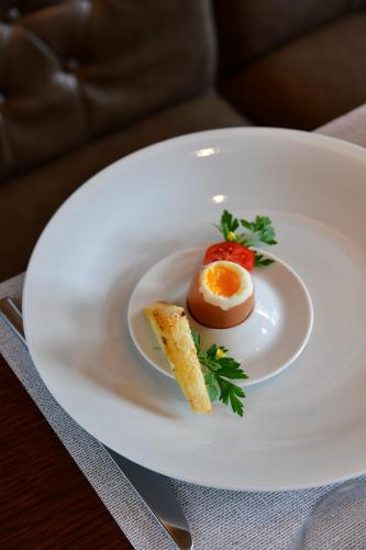 a white plate with an egg and a tomato on it at Metropolitan Boutique Hotel in Kraków