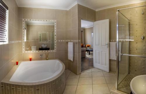 Lalapanzi Guest Lodge في بورت اليزابيث: حمام مع حوض استحمام ودش ومغسلة