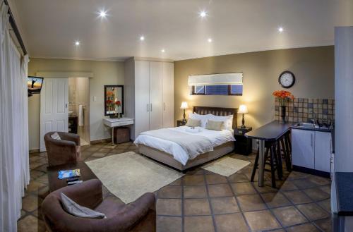 a bedroom with a bed and a desk and chairs at Lalapanzi Guest Lodge in Port Elizabeth