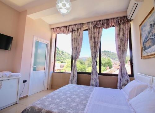 a bedroom with a bed and a large window at Hotel Orestiada in Berat
