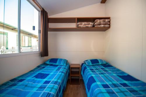 two beds in a small room with a window at Camping Media Mobile Homes in Brioni Sunny Camping in Pula
