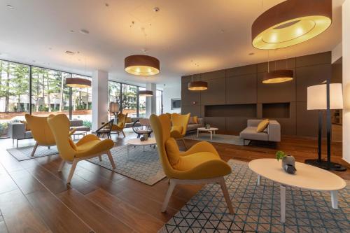 a living room with yellow chairs and tables at Hotel Park Plava Laguna in Poreč