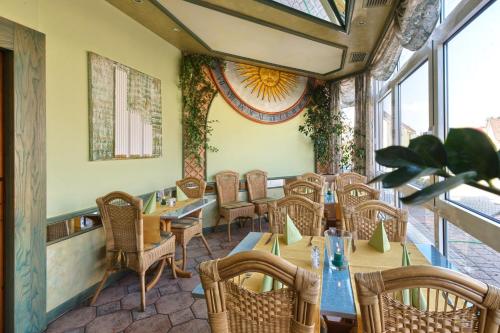 a restaurant with tables and chairs and windows at Hotel Mythos in Rust