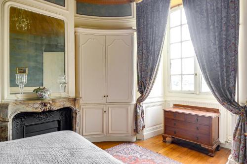 a bedroom with a bed and a dresser and a fireplace at Château d'Ermenonville in Ermenonville