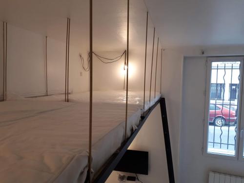 une chambre avec un lit dans une chambre avec une fenêtre dans l'établissement Enjoyable 20m² MONTREUIL 5 minutes Paris, à Montreuil